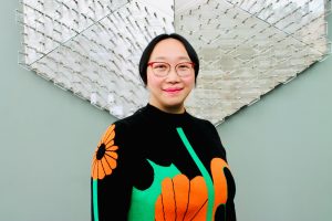 Ting Fu in a black sweater with flowers against silver art