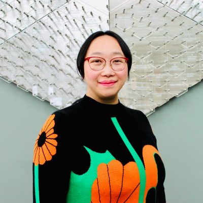 Ting Fu in a black sweater with flowers against silver art