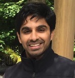 Sinha wearing a black shirt against a green, wooded, background