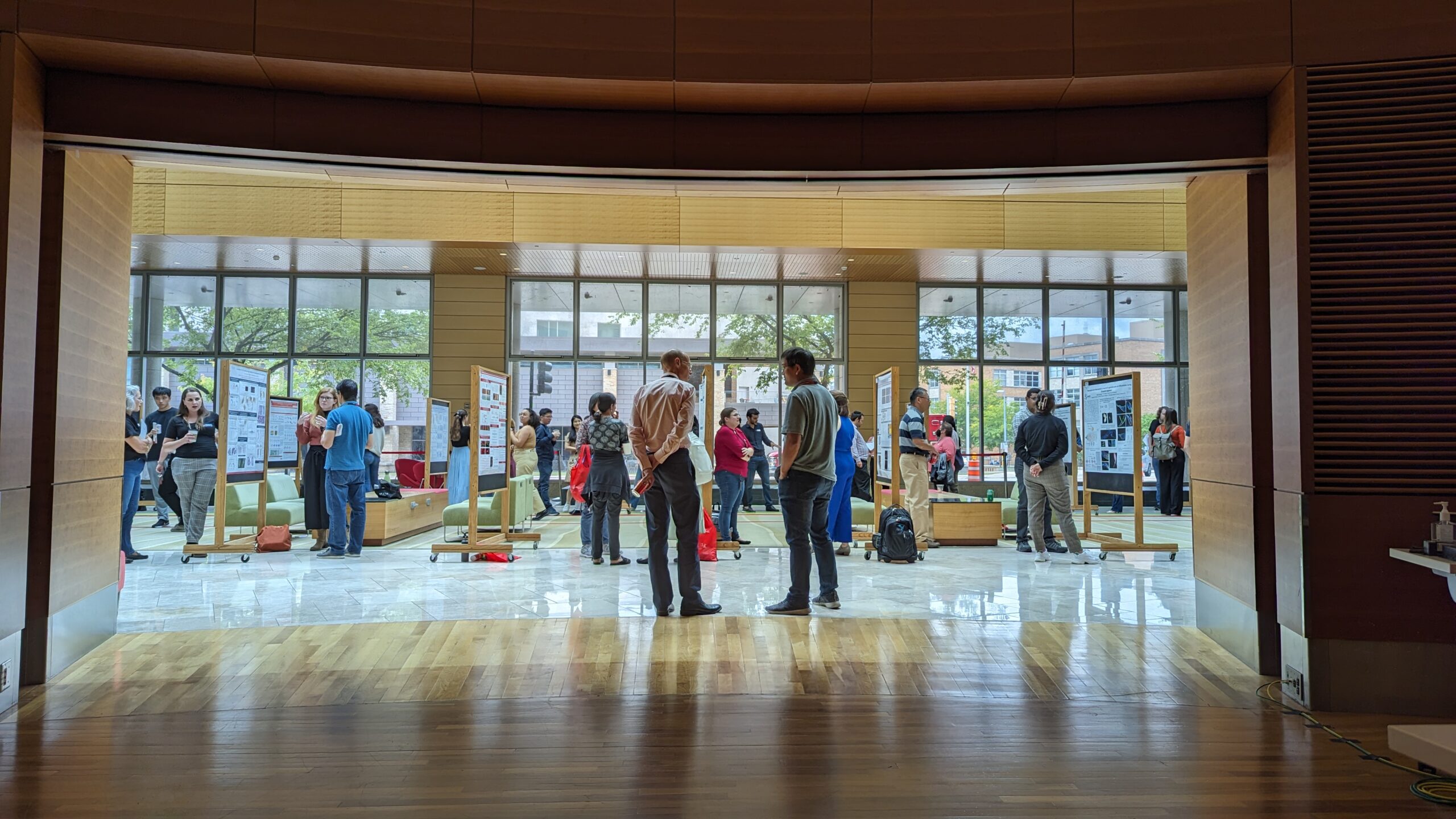 a bright window behind posters and people standing at an event